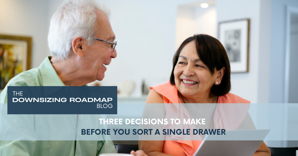 A couple sitting at a kitchen table with a notepad and pen, planning their next steps before downsizing their home.